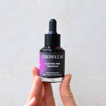 Hand holding a bottle of Chroma Lab Electric Pink Molecule hair toning concentrate against a plain background
