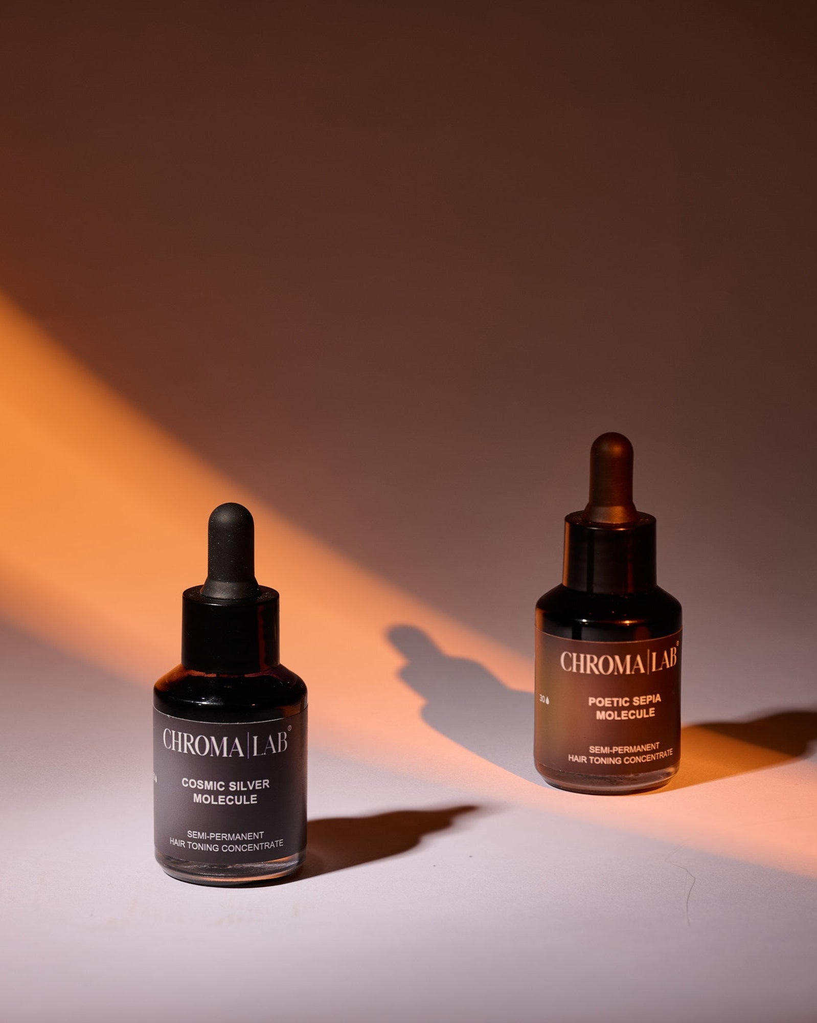 Two bottles of Chromalab Molecules hair toning concentrated on a gradient background with warm lighting.
