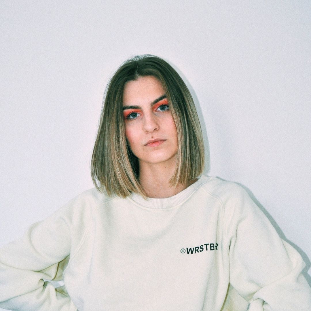 Person wearing a white sweatshirt with 'WRSTBR' branding against a plain background