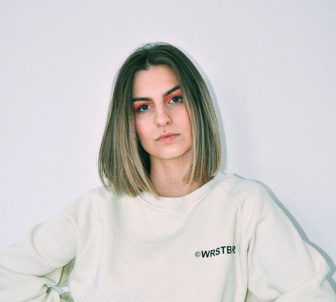 Person wearing a white sweatshirt with 'WRSTBR' branding against a plain background