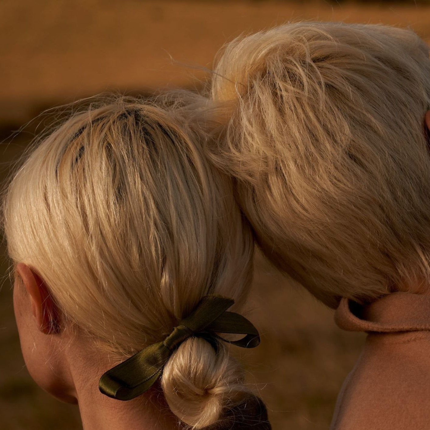Close-up of a person with blonde hair tied back with a green scrunchie against a blurred background