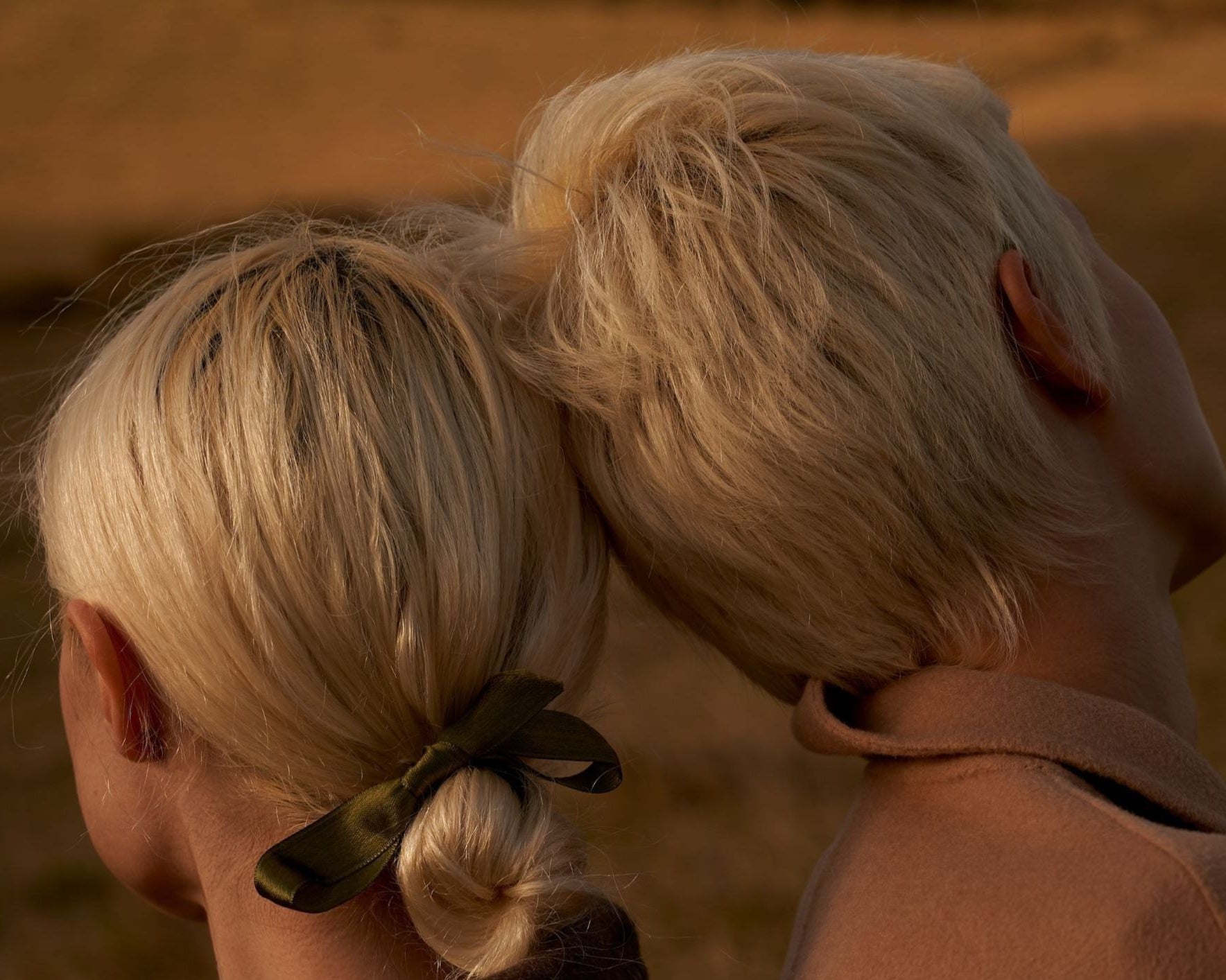 Close-up of a person with blonde hair tied back with a green scrunchie against a blurred background