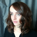 Woman with shoulder-length brown hair against a plain background