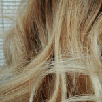Close-up of wavy blonde hair with a blurred background