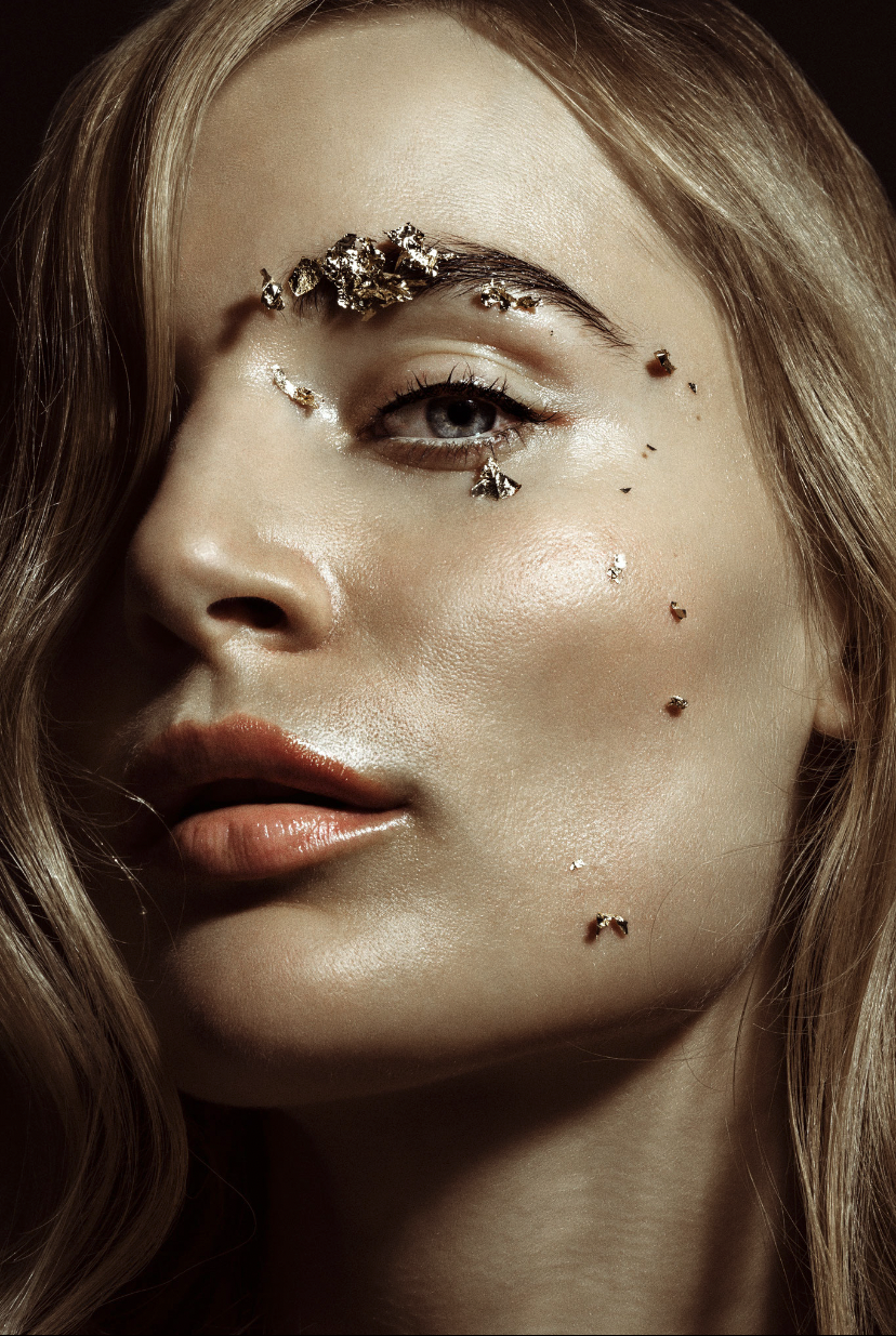 Close-up of a woman's face with decorative elements on her face against a dark background